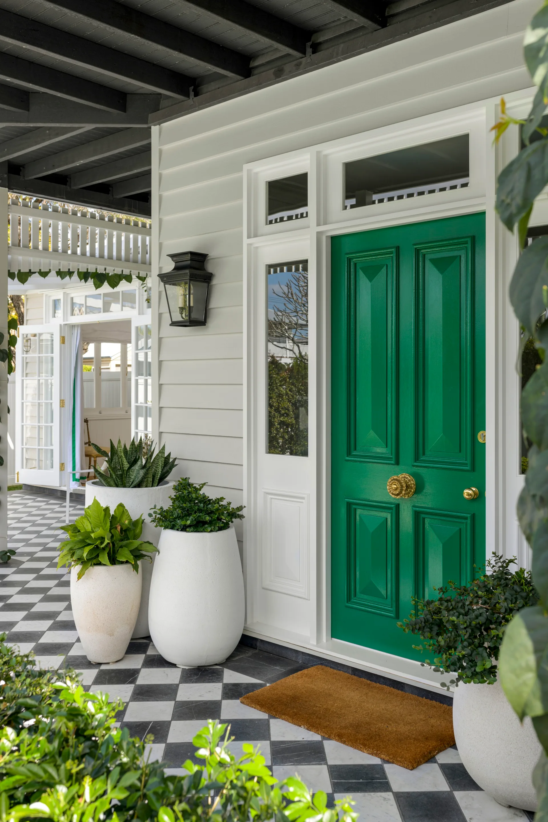 A vibrant green front door with a classic checked floor.