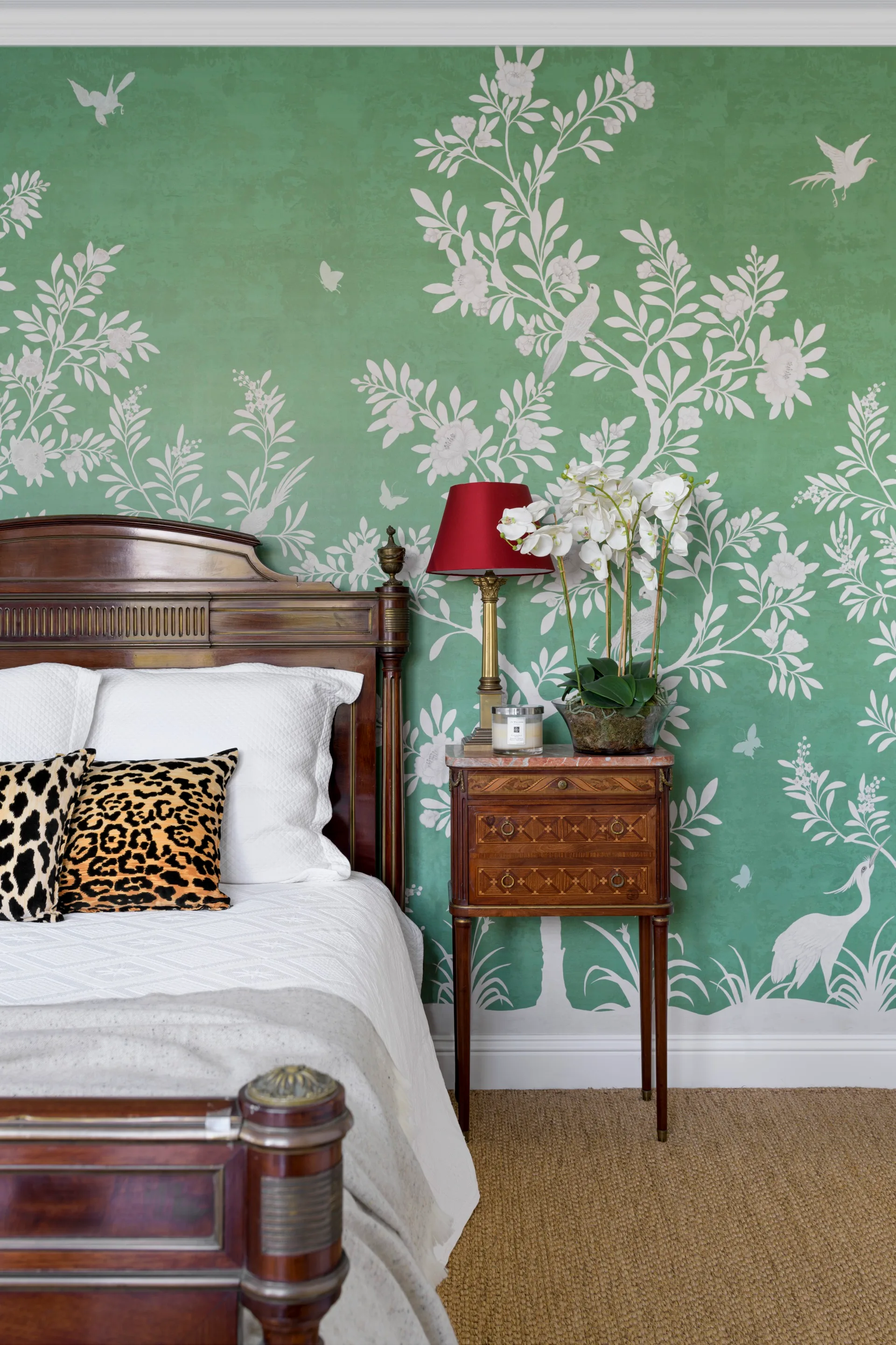 A guest bedroom with green floral wallpaper and timber bed.