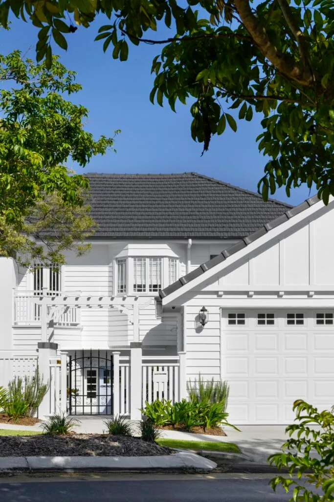 A white two-storey bungalow with stucco timber cladding.