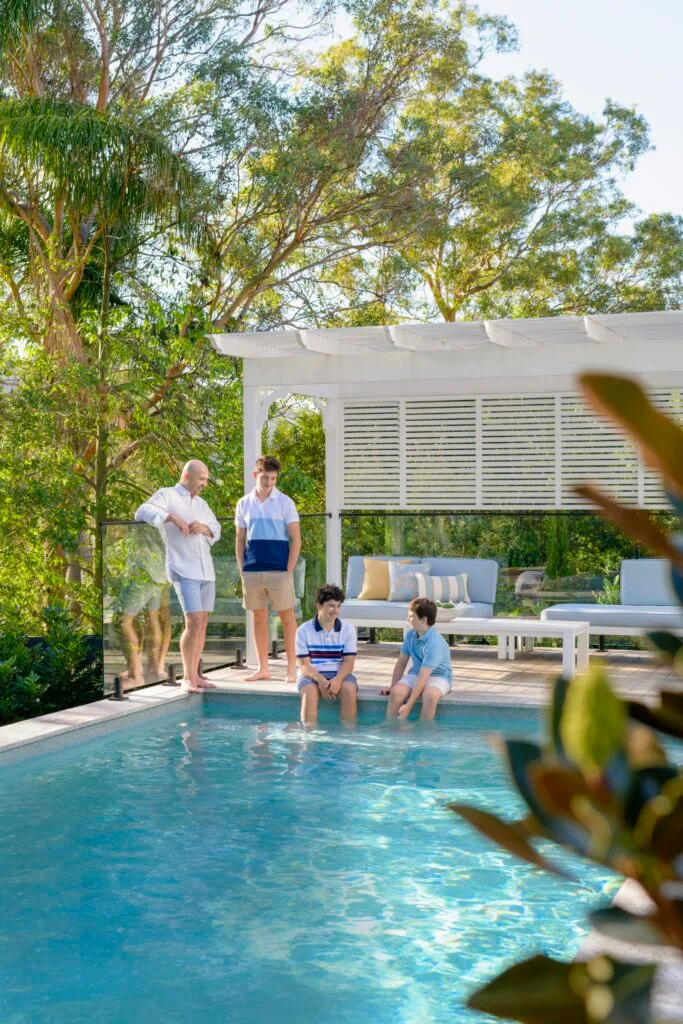 A family sitting by the pool beneath a white cabana.