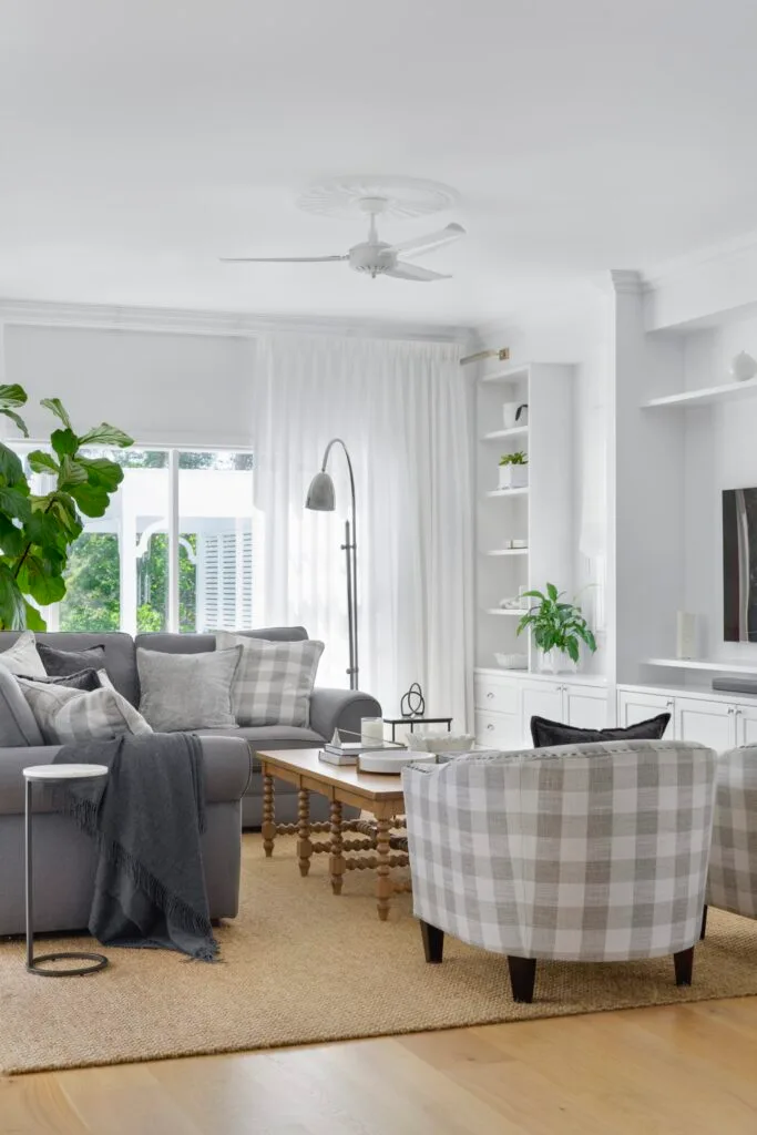 A classic white living room with grey and checked sofas and open shelving.