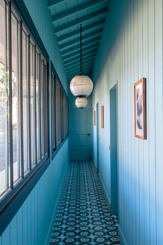 A blue hallway with patterned floor tiles and hanging globe pendants.