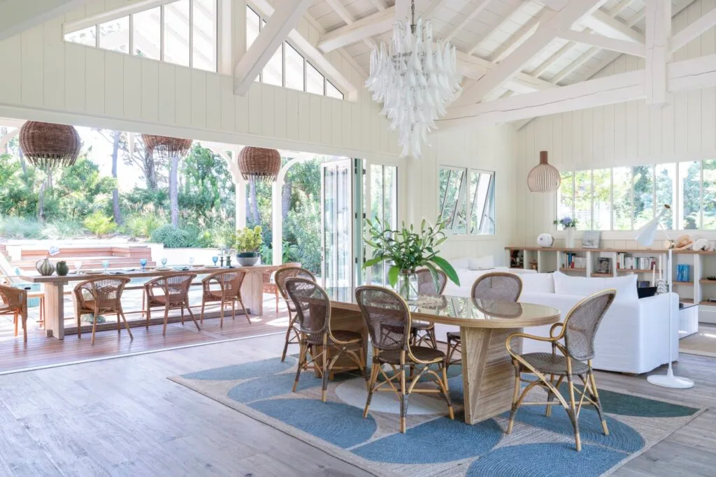 A dining area leading to an outdoor alfresco area with wicker furniture and a raised white ceiling.