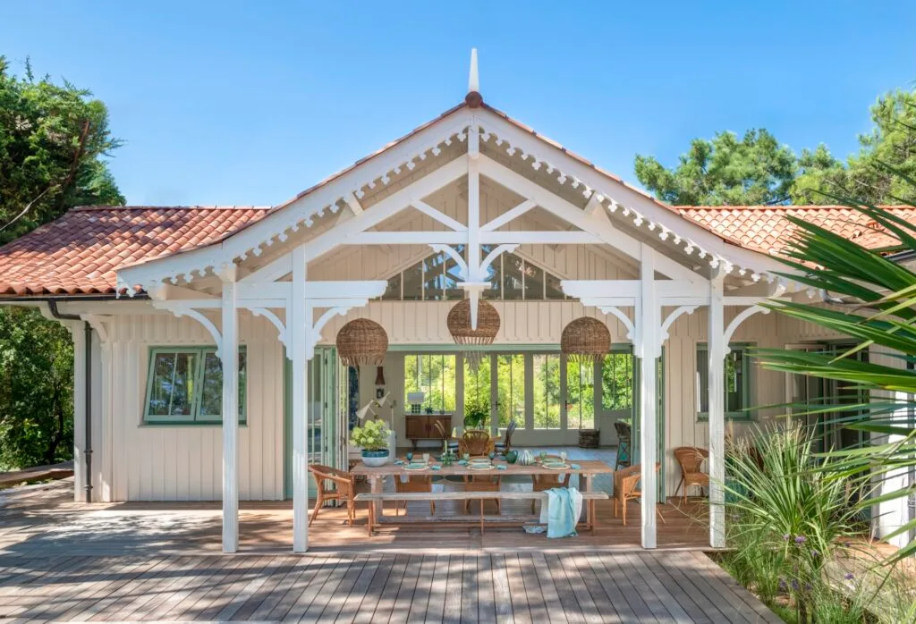 An alfresco area covered by a pitched roof with decorative wood details.