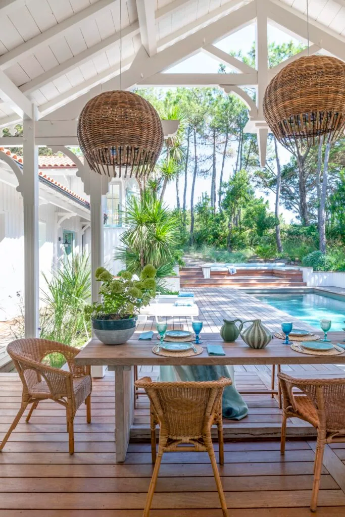 An outdoor alfresco area with wicker furniture overlooking a pool.