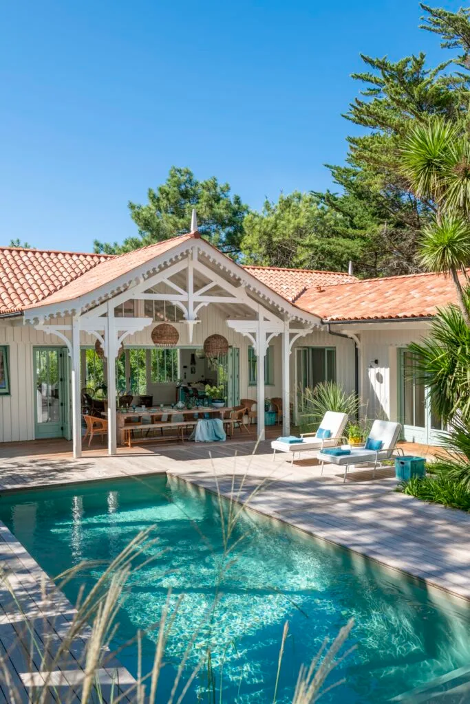 A swimming pool and outdoor alfresco area covered by a pitched roof.