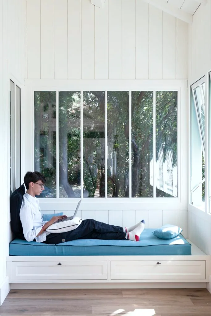 Lachlan reading on a blue window seat overlooking a garden.