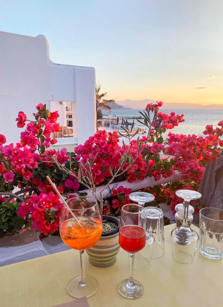 Two aperitifs on a table overlooking a sunset ocean view.