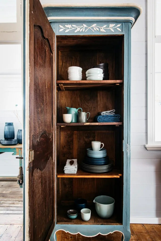 An open cupboard with coloured ceramic tableware.