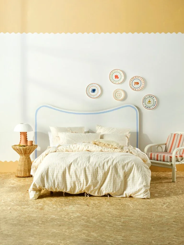 A bright yellow bedroom with a curved blue bed.