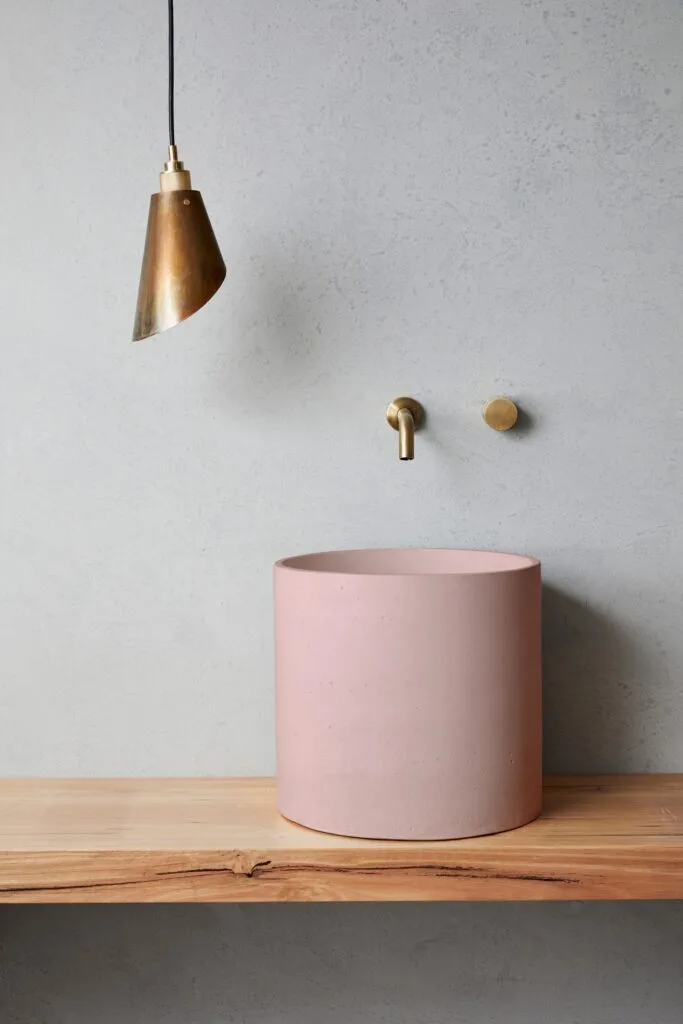 A rounded pink basin and gold tapware.