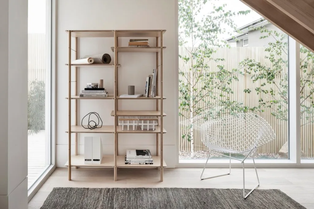 A wooden open bookshelf and white iron chair.