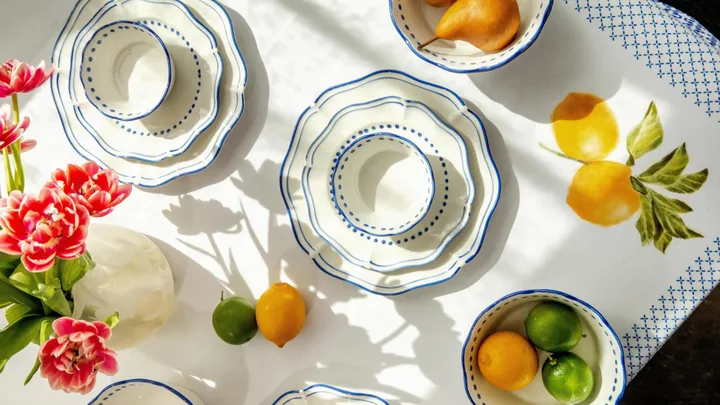 Blue and white scalloped plates on a table decorated with a lemon-printed tablecloth