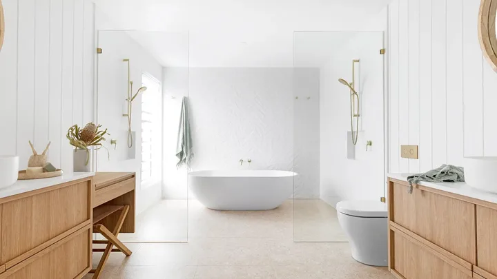 Contemporary coastal bathroom with a central freestanding tub and double showers on either side.