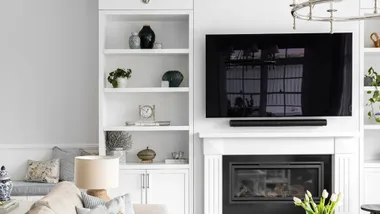 Flat screen TV wall-mounted above a fireplace in a Hamptons style living room.