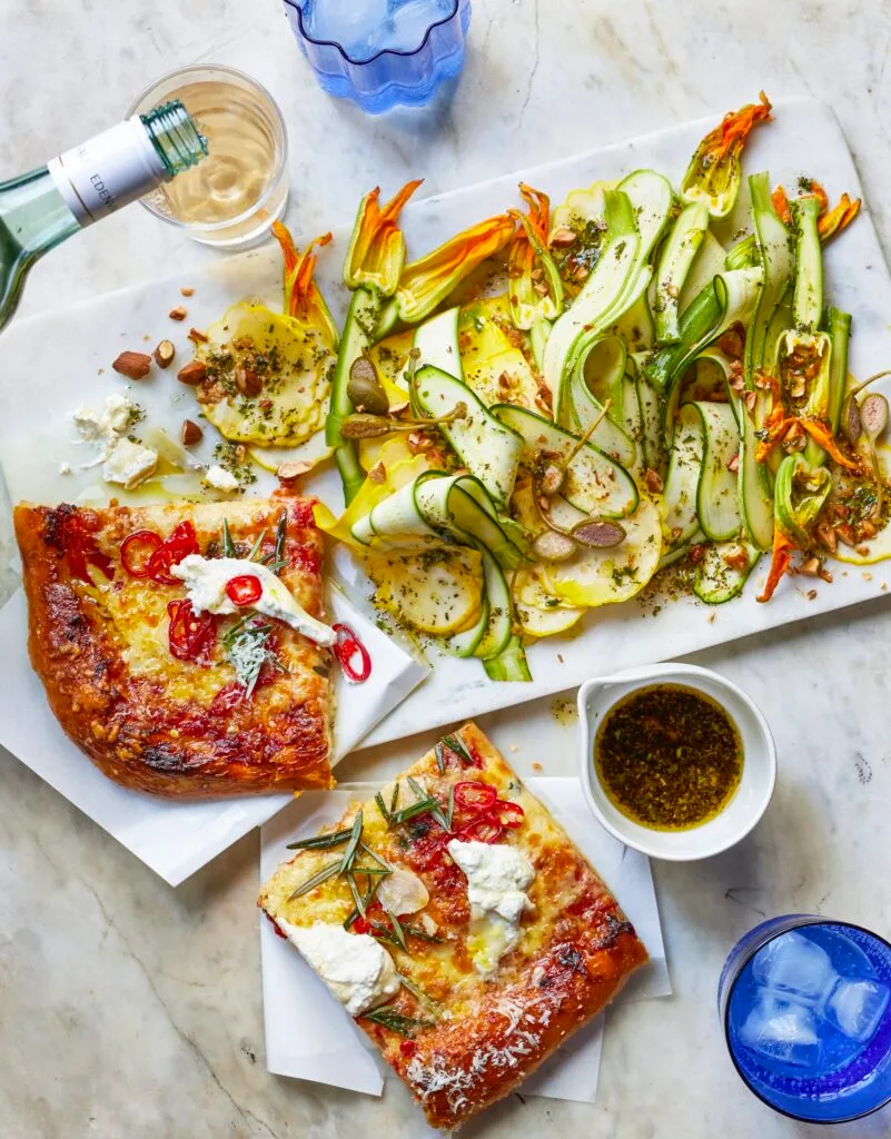 A marinated zucchini almond salad beside slices of pizza.