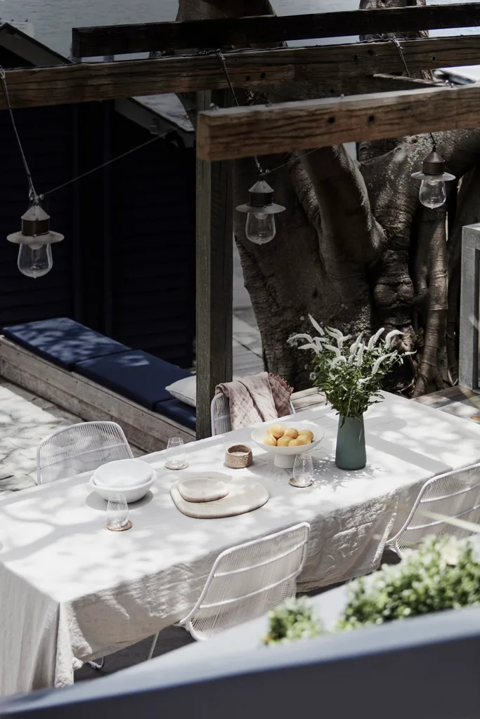 An outdoor alfresco area with a dining table and hanging festoon lights.