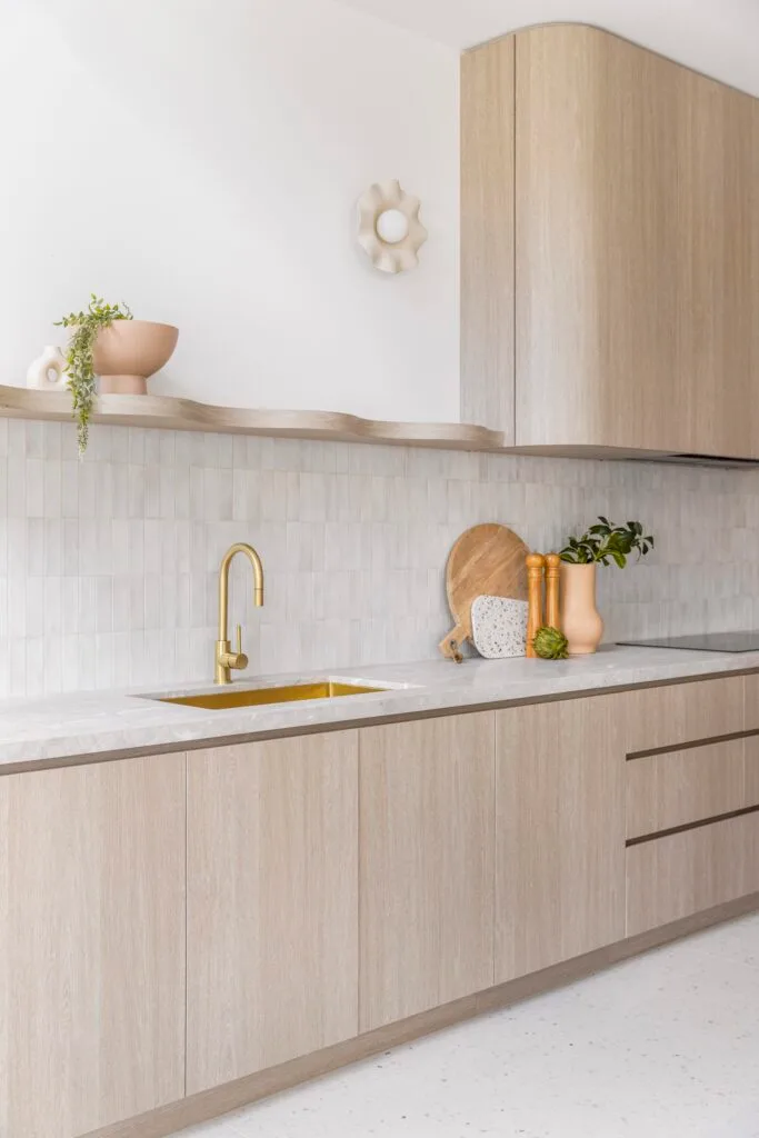 A sink with brass tapware by stone-style benchtops and a subway tile splashback.