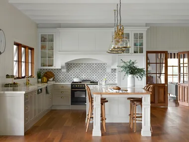 A country kitchen with blackbutt timber floors, a timber topped table and brass accents.
