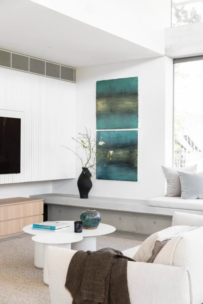 A neutral style family living room with blue wall art and a bench.