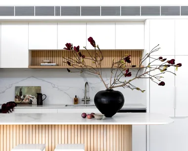 The kitchen with a fluted timber island and black vase.