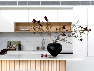 The kitchen with a fluted timber island and black vase.