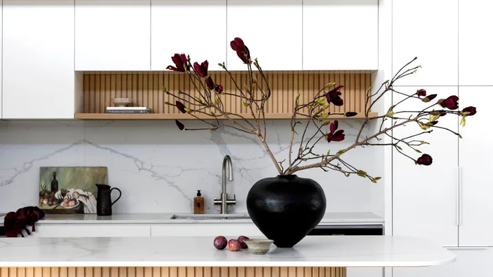 The kitchen with a fluted timber island and black vase.