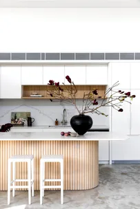 The kitchen with a fluted timber island and black vase.