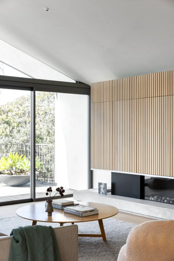 A living room with timber fluted wall details looking onto the garden.