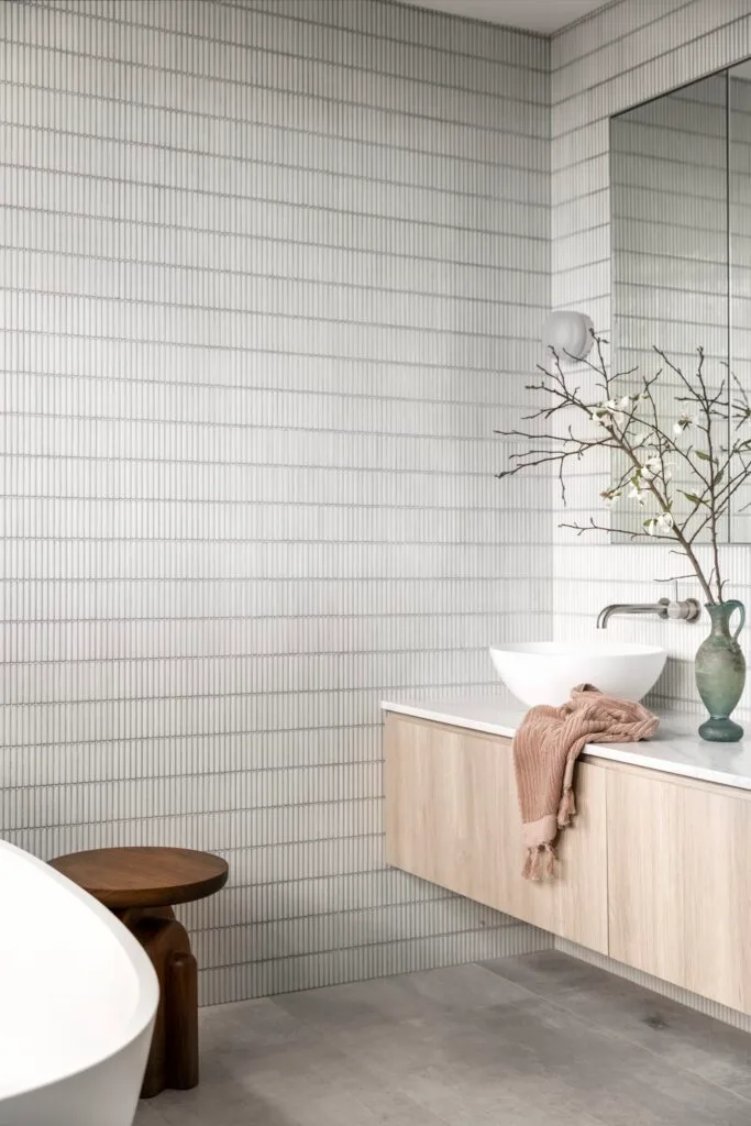 The ensuite with grey finger tile walls and a timber vanity.