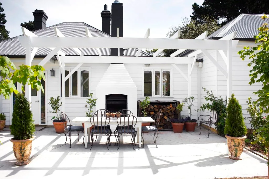 A classic white alfresco area with a stacked outdoor fireplace.