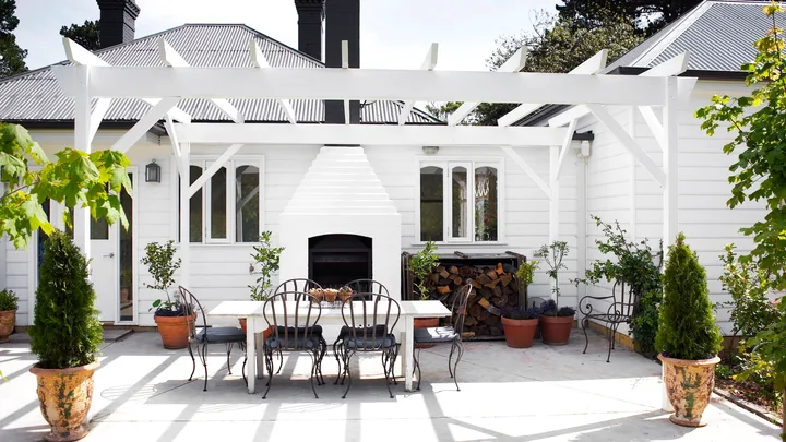 A classic white alfresco area with a stacked outdoor fireplace.