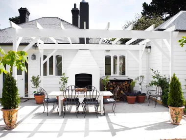 A classic white alfresco area with a stacked outdoor fireplace.