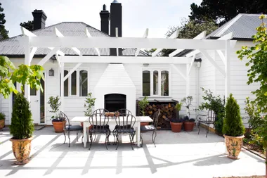 A classic white alfresco area with a stacked outdoor fireplace.