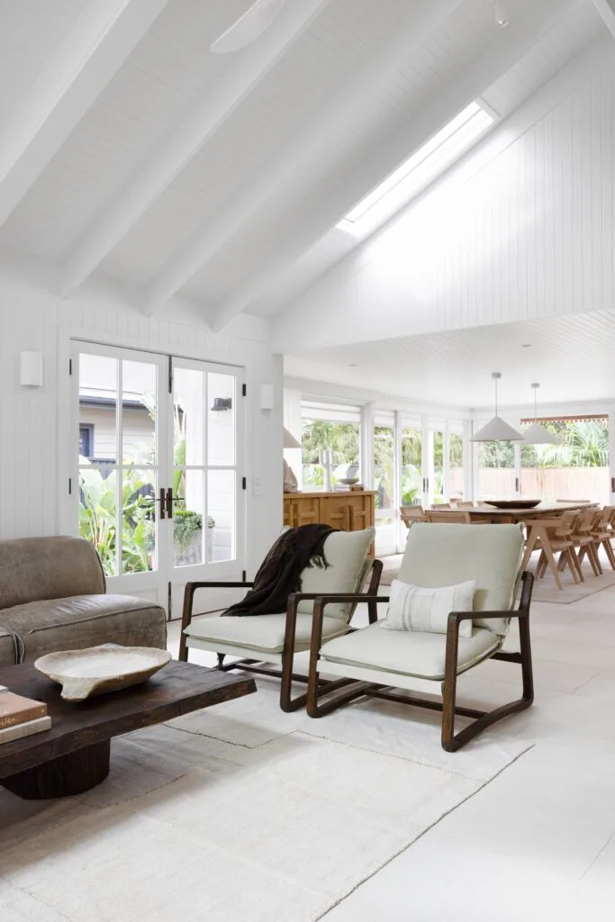 A living and dining area with white vaulted ceilings and timber furniture.