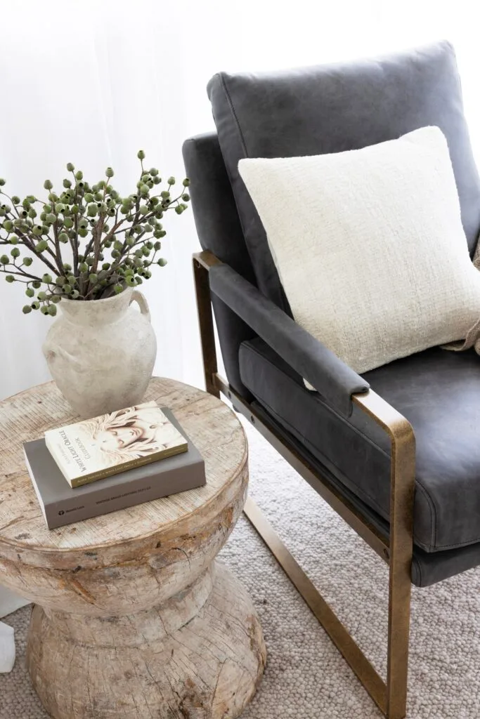 A reading nook with a wooden stool and grey armchair.