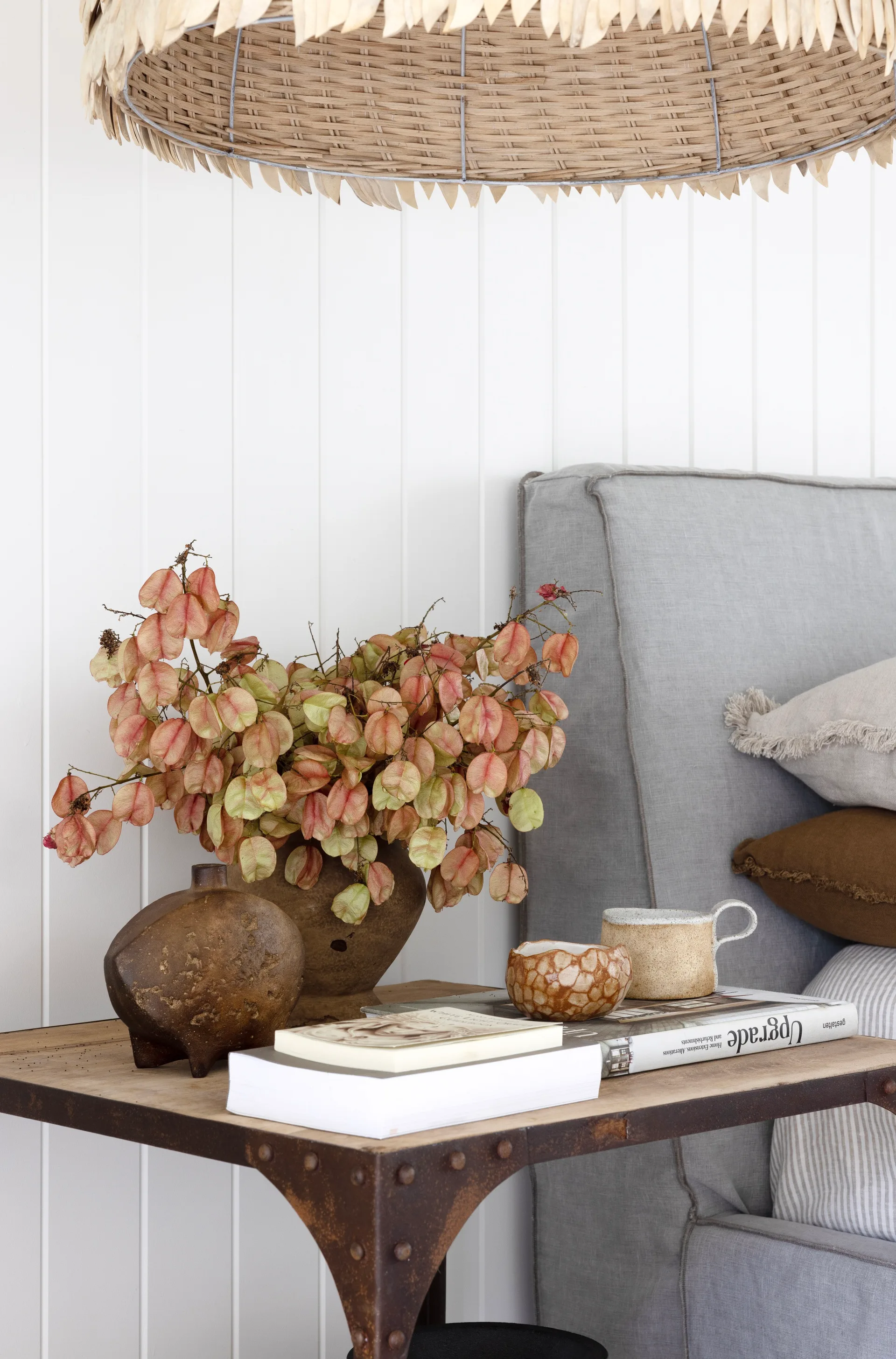 A bedside table with books and rustic vessels.