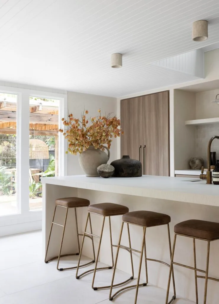 Contemporary wabi sabi kitchen with brown upholstered bar stools and large windows