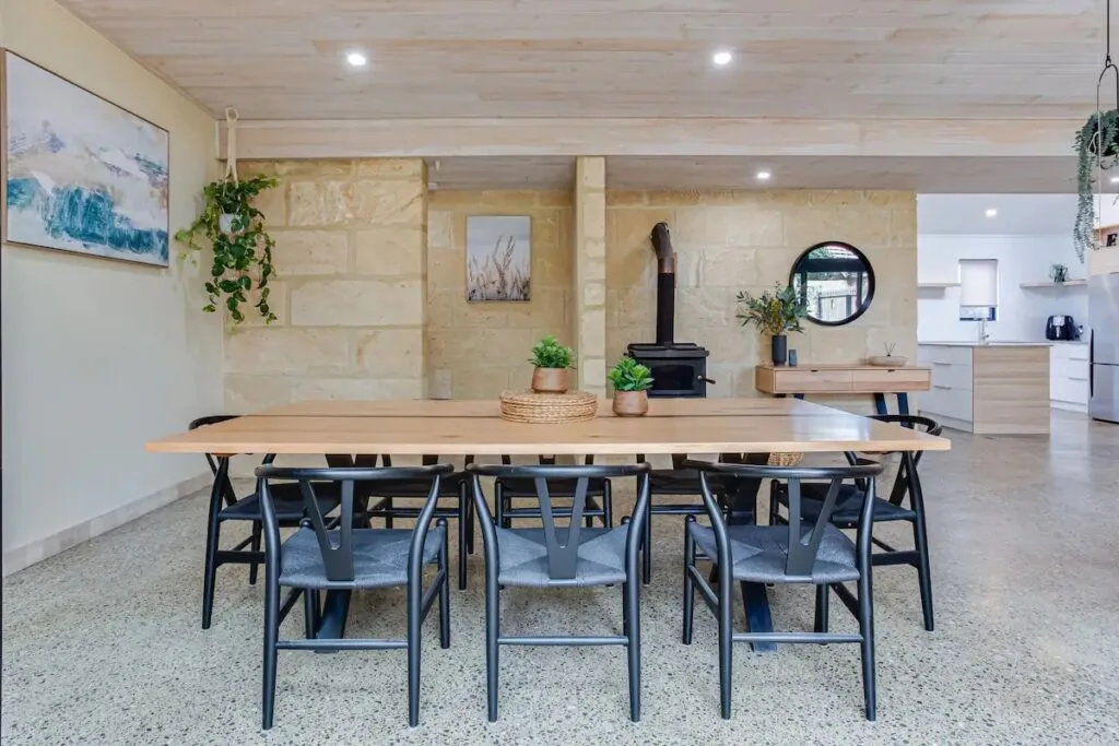 A limestone dining room with concrete floors and a timber table.