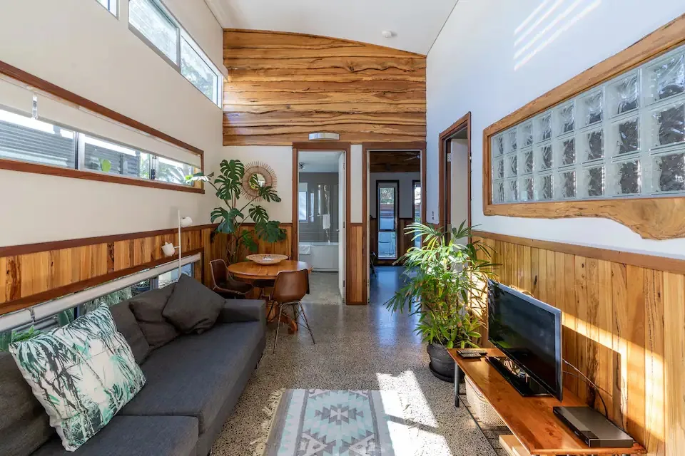 A retro-style studio living room with timber panels and a block glass wall.