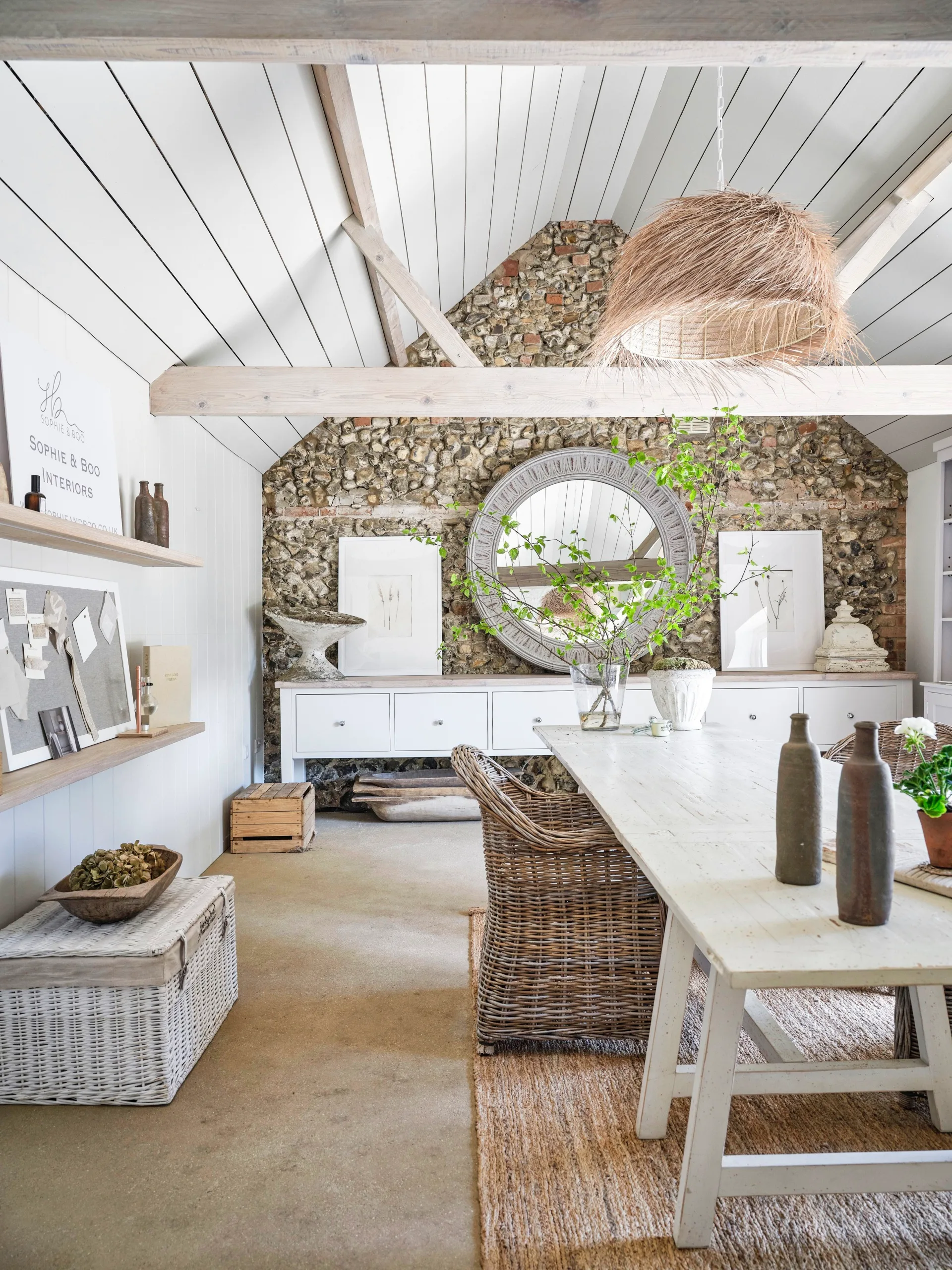 A Scandi-style cottage studio with exposed beams, a stone back wall and white panels.