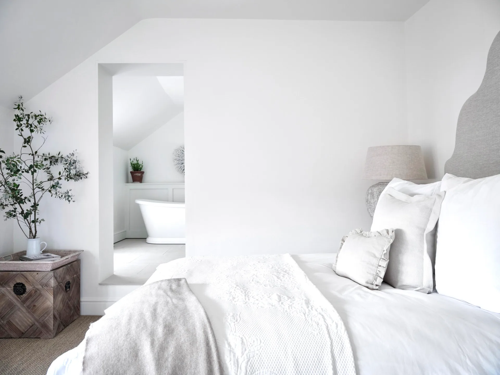 An all-white guest bedroom with an adjoining ensuite.