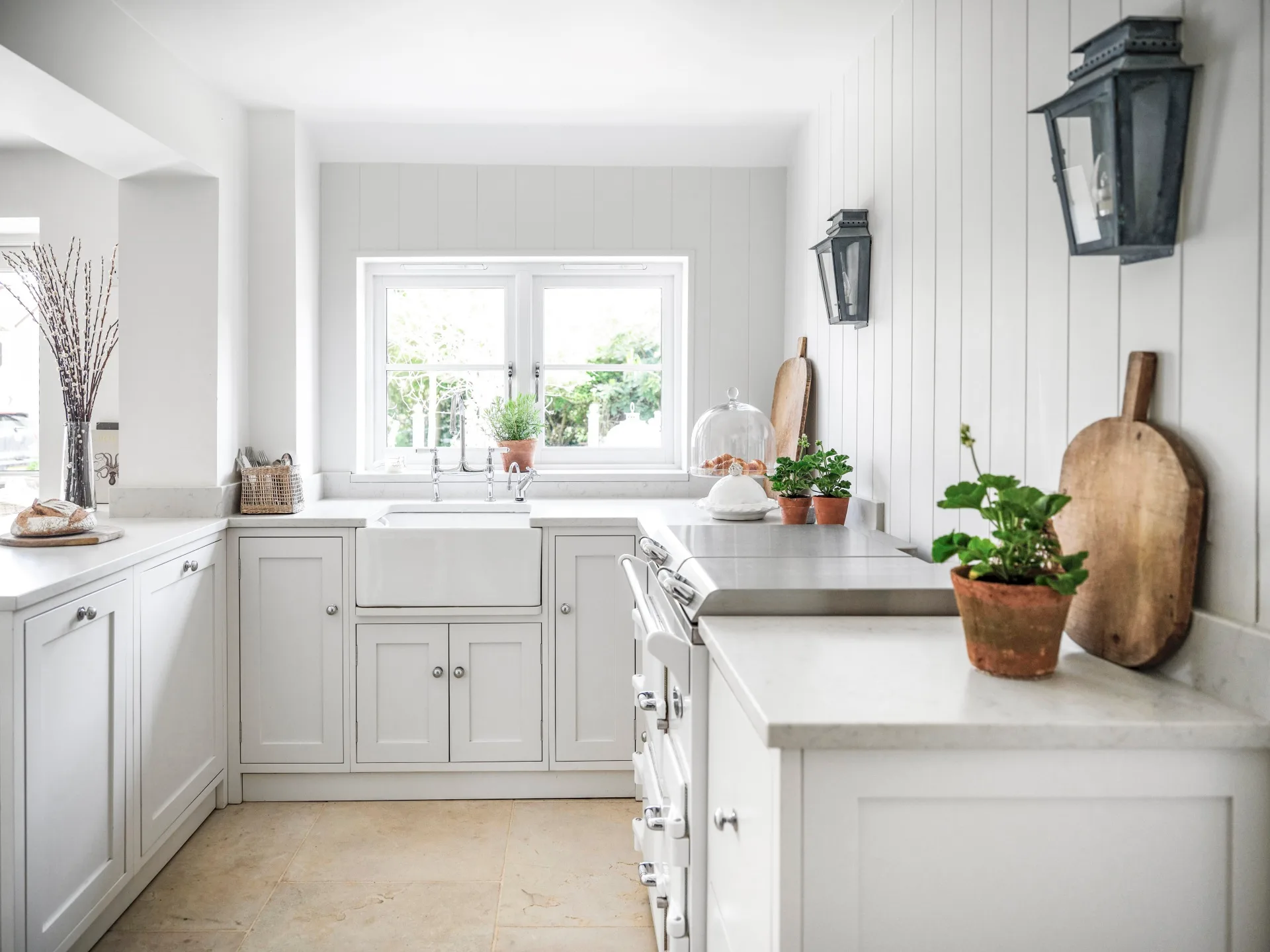 An all-white country kitchen with shaker-style cabinets and a farmhouse sink.