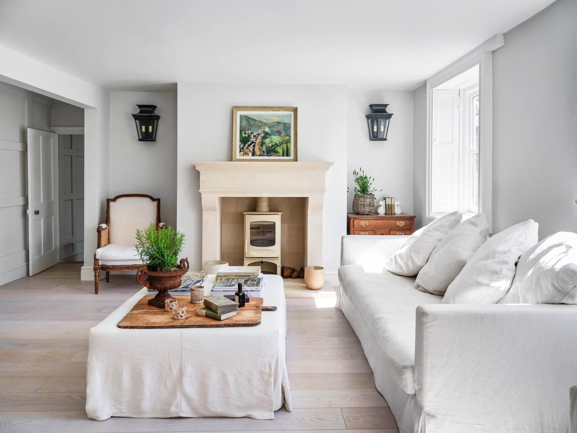 A modern country living room with a stone fireplace and white sofas.