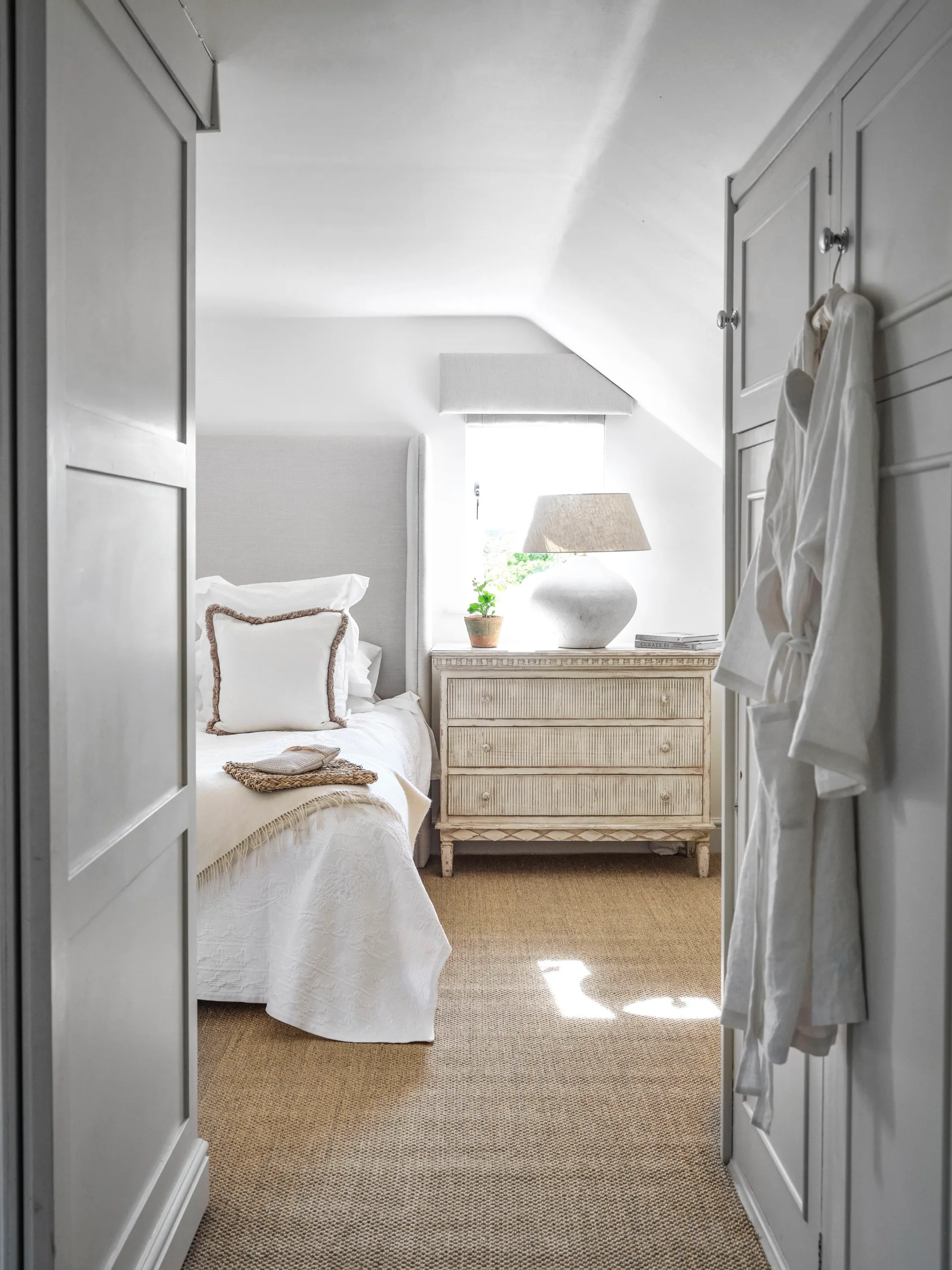 An all-white main bedroom with panelled cupboards.
