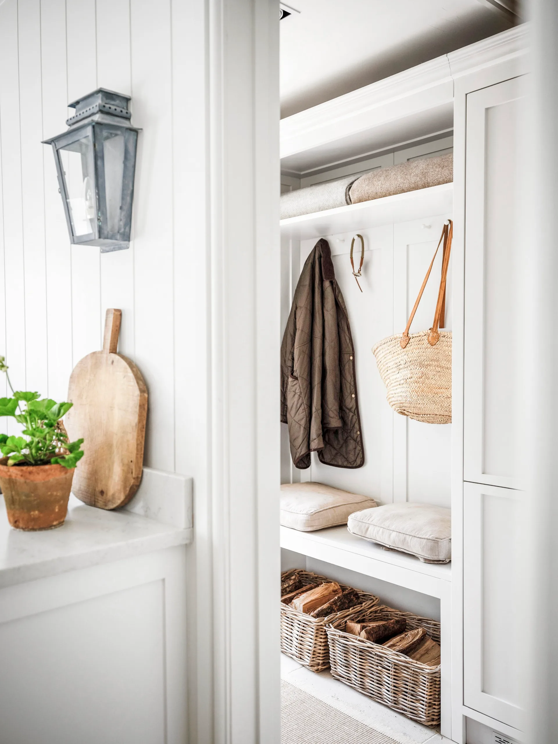 A mudroom with wall panelling, a bench and basket storage.