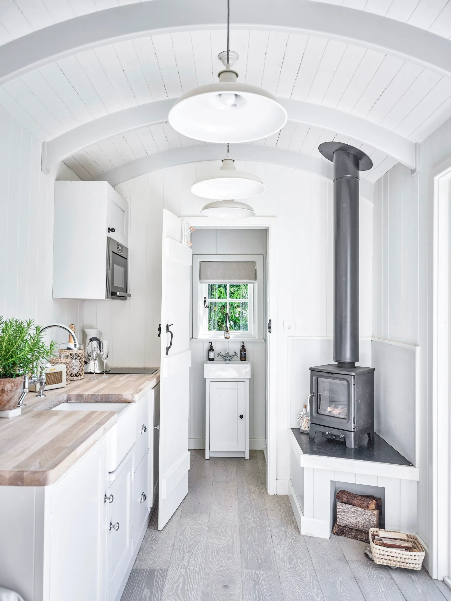 A modern shepherd's hut with a kitchenette, hearth and bathroom.