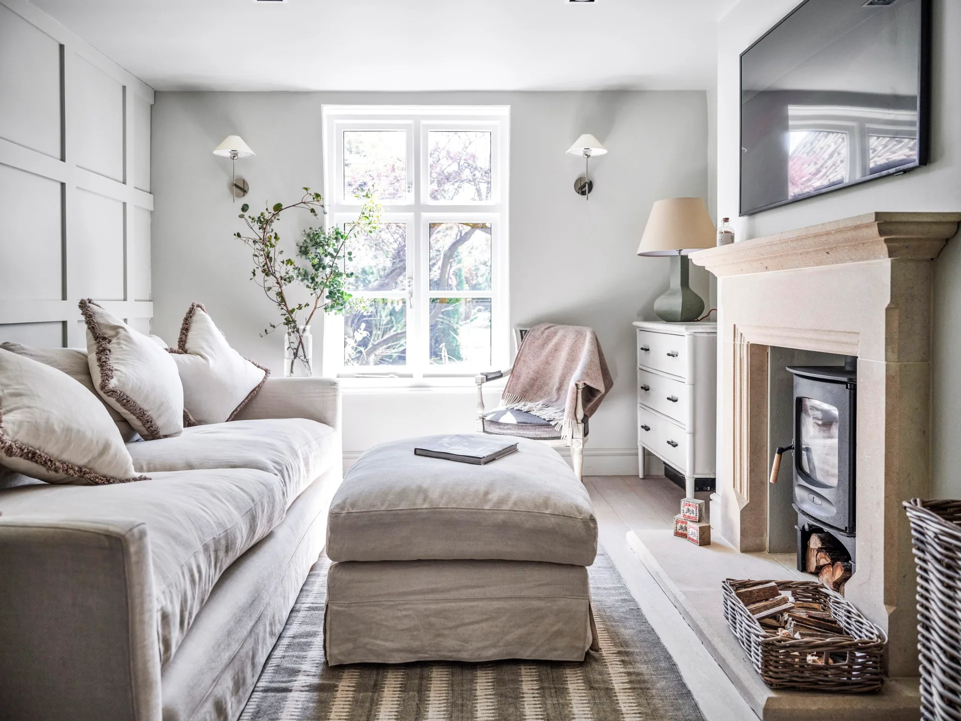 A snug sitting area with a white sofa and stone fireplace.