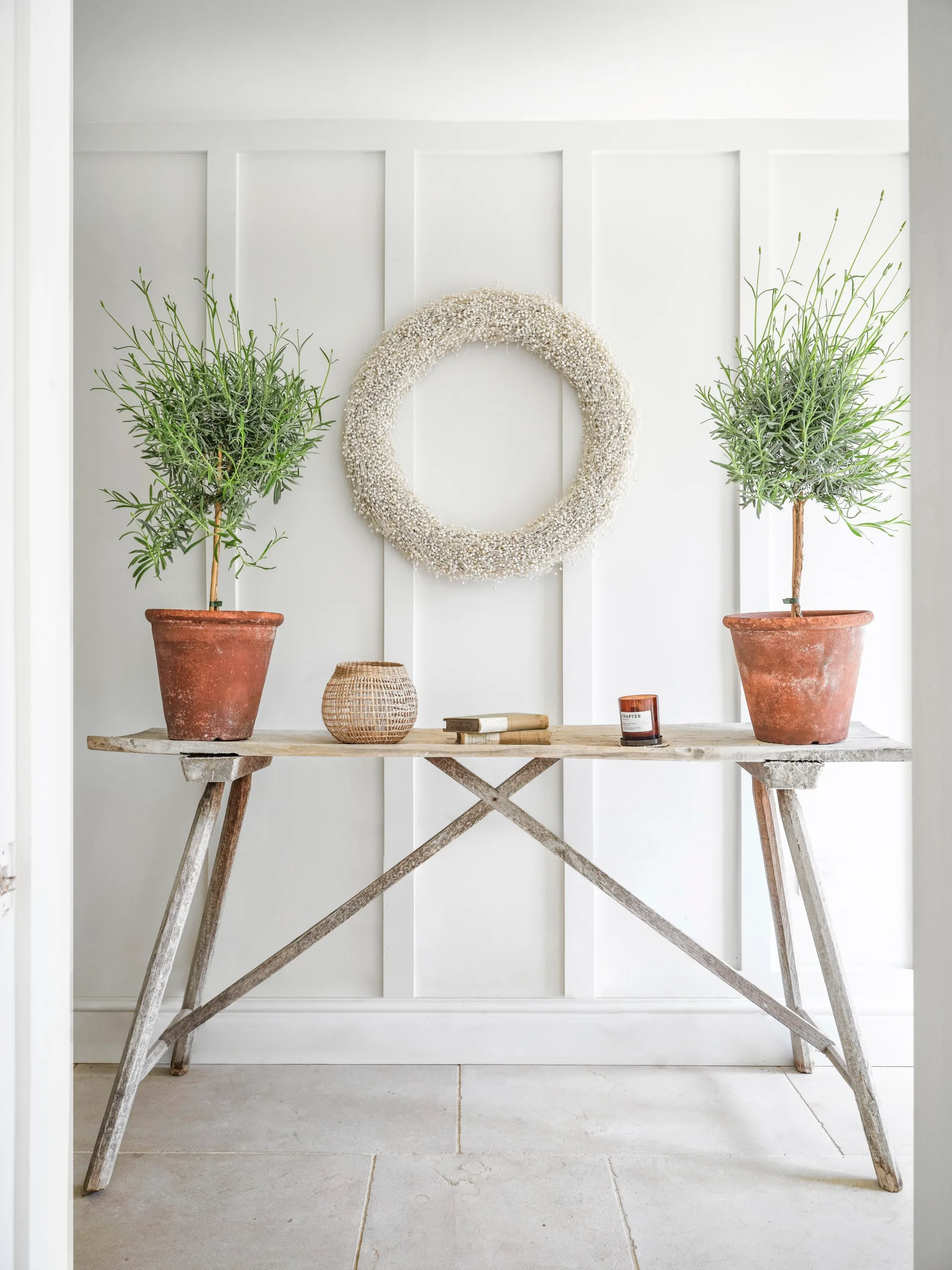 A white panelled hallway with a timber table and pot plants.