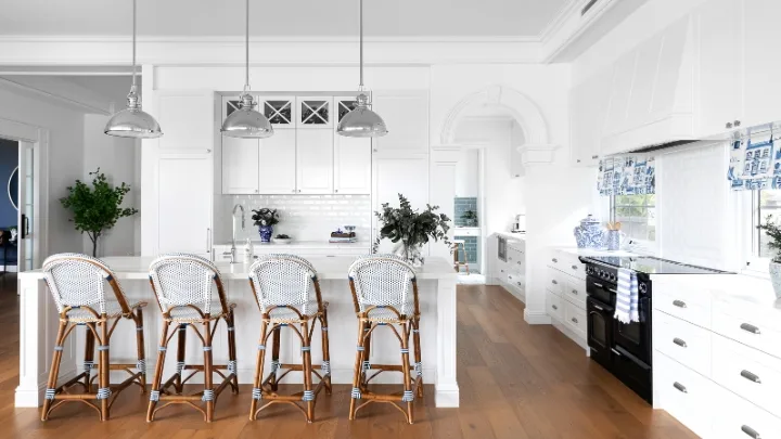 white hamptons kitchen with bar stools and 3 silver pendant lights